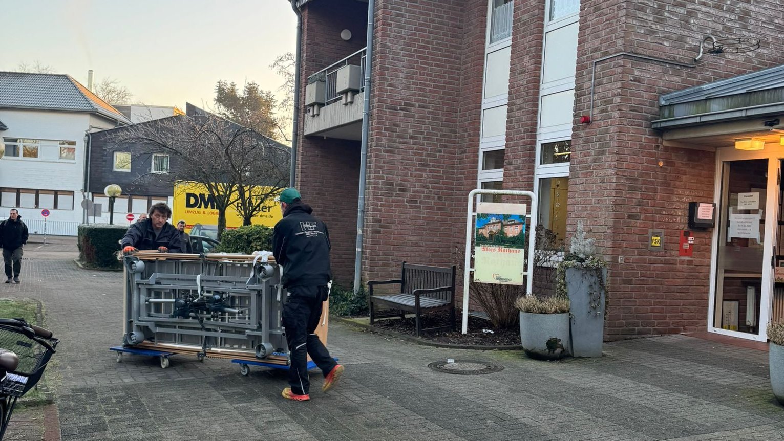 Das Bild zeigt zwei Männer beim Umzug eines Pflegebettes in die neue Einrichtung.