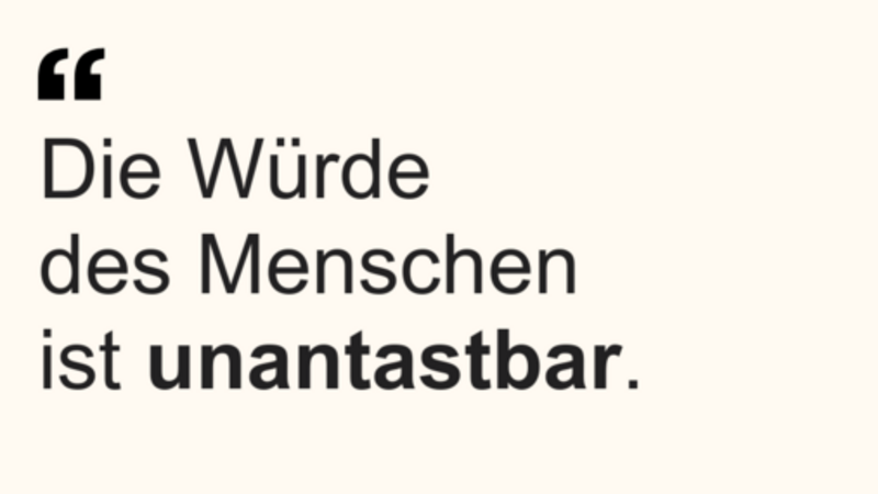 Das Bild enthält ein Zitat aus Artikel 1 des Grundgesetzes für die Bundesrepublik Deutschland: „Die Würde des Menschen ist unantastbar.“