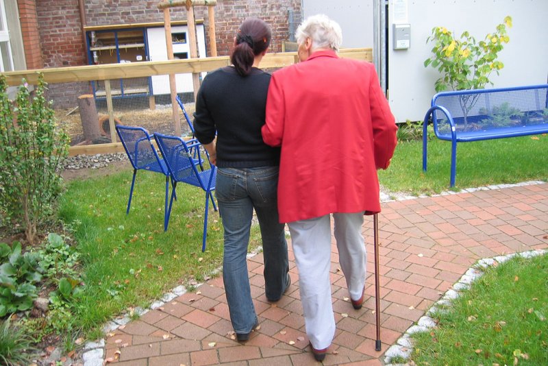 Das Bild zeigt eine Seniorin beim Spaziergang mit einer Betreuerin.