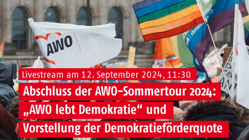 Auf dem Foto ist eine Versammlung von Menschen vor einem Gebäude zu sehen, das wie der Reichstag in Berlin aussieht. Die Menschen halten verschiedene Fahnen und Banner, darunter eines mit dem Logo “AWO” (Arbeiterwohlfahrt). Im Mittelpunkt steht ein großes Banner mit dem Text: “Livestream am 12. September 2024, 11:30. Abschluss der AWO-Sommertour 2024: ‘AWO lebt Demokratie’ und Vorstellung der Demokratieförderquote.” Unten rechts ist auch die Website “awo.org” zu sehen.