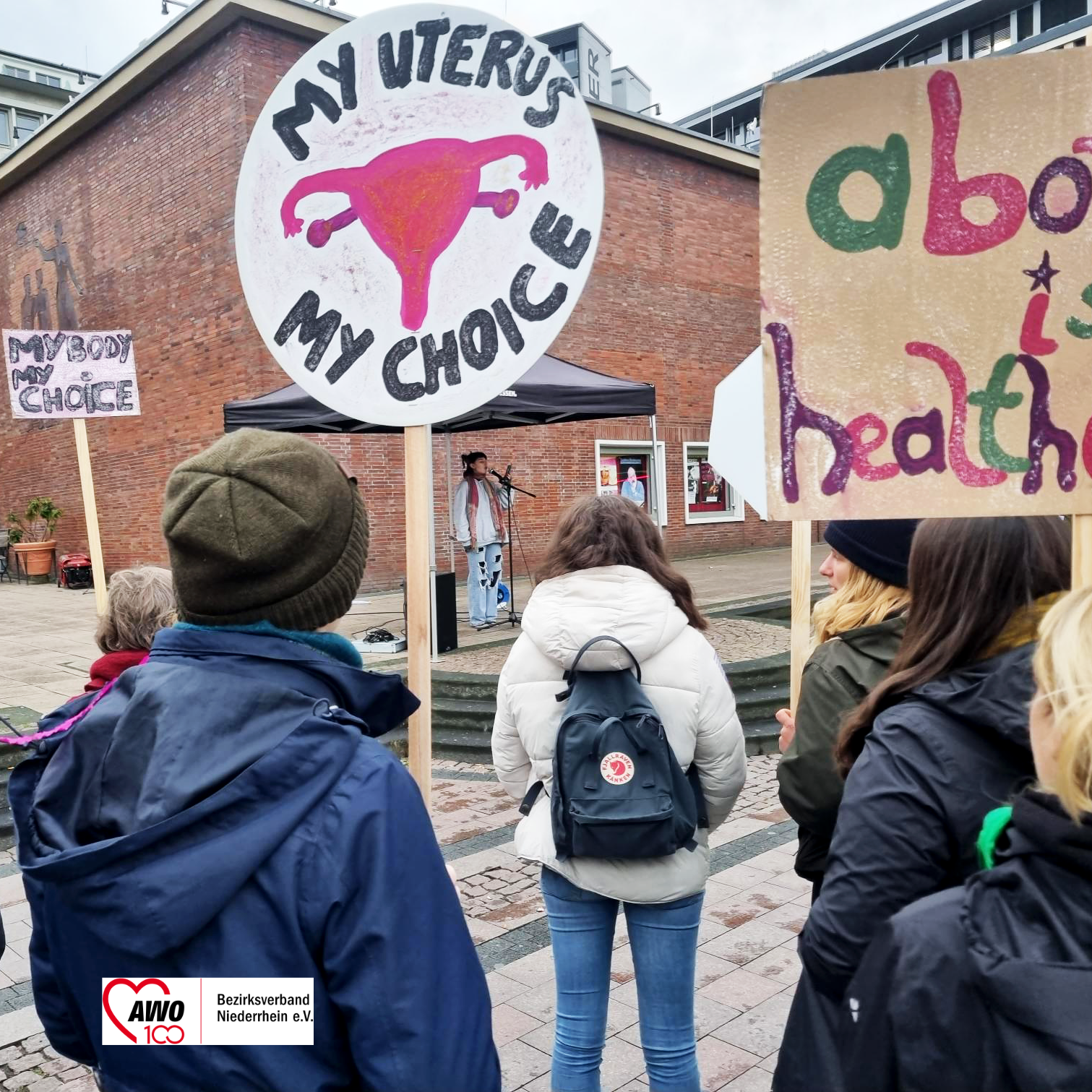 Das Foto zeigt Demo-Teilnehmende und ein Schild mit dem Text "My uterus! My Choice"